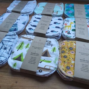 Puede incluir: Un juego de 10 toallitas reutilizables hechas de tela 100% algodón. Las toallitas están empaquetadas en pilas de 5 y presentan diferentes patrones coloridos, que incluyen diseños de acampada, animales y florales. El empaque incluye el nombre de la marca "Mary Makes" y el texto "Toallitas reutilizables 100% algodón".