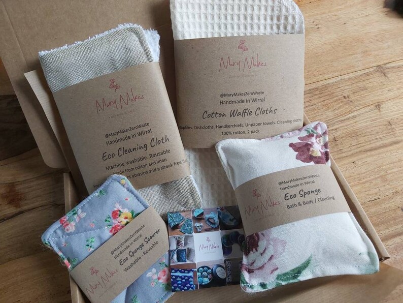 May include: A box filled with eco-friendly cleaning and bath products. The products are made by Mary Makes Zero Waste and include a cotton waffle cloth, an eco cleaning cloth, an eco sponge scourer, and an eco sponge. The products are all handmade in Wirral.