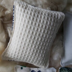 May include: A white waffle-textured throw pillow with a blue and white striped trim.