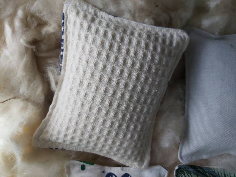 May include: A white waffle-textured throw pillow with a blue and white striped trim.