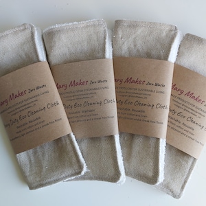 Puede incluir: Cuatro pa&ntilde;os de limpieza ecol&oacute;gicos beige y blancos con etiquetas de papel marr&oacute;n que dicen "Mary Makes Zero Waste" y "Duty Eco Cleaning Cloth". Las etiquetas tambi&eacute;n incluyen informaci&oacute;n sobre el producto que es lavable, reutilizable y hecho de algod&oacute;n y lino.