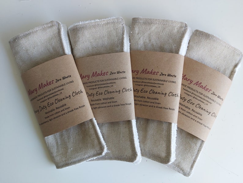 Puede incluir: Cuatro pa&ntilde;os de limpieza ecol&oacute;gicos beige y blancos con etiquetas de papel marr&oacute;n que dicen "Mary Makes Zero Waste" y "Duty Eco Cleaning Cloth". Las etiquetas tambi&eacute;n incluyen informaci&oacute;n sobre el producto que es lavable, reutilizable y hecho de algod&oacute;n y lino.