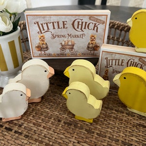 May include: Wooden chick figurines in yellow and white with a sign that reads "Little Chick Spring Market" Open Daily Flowers, Honey, Eggs, Produce.