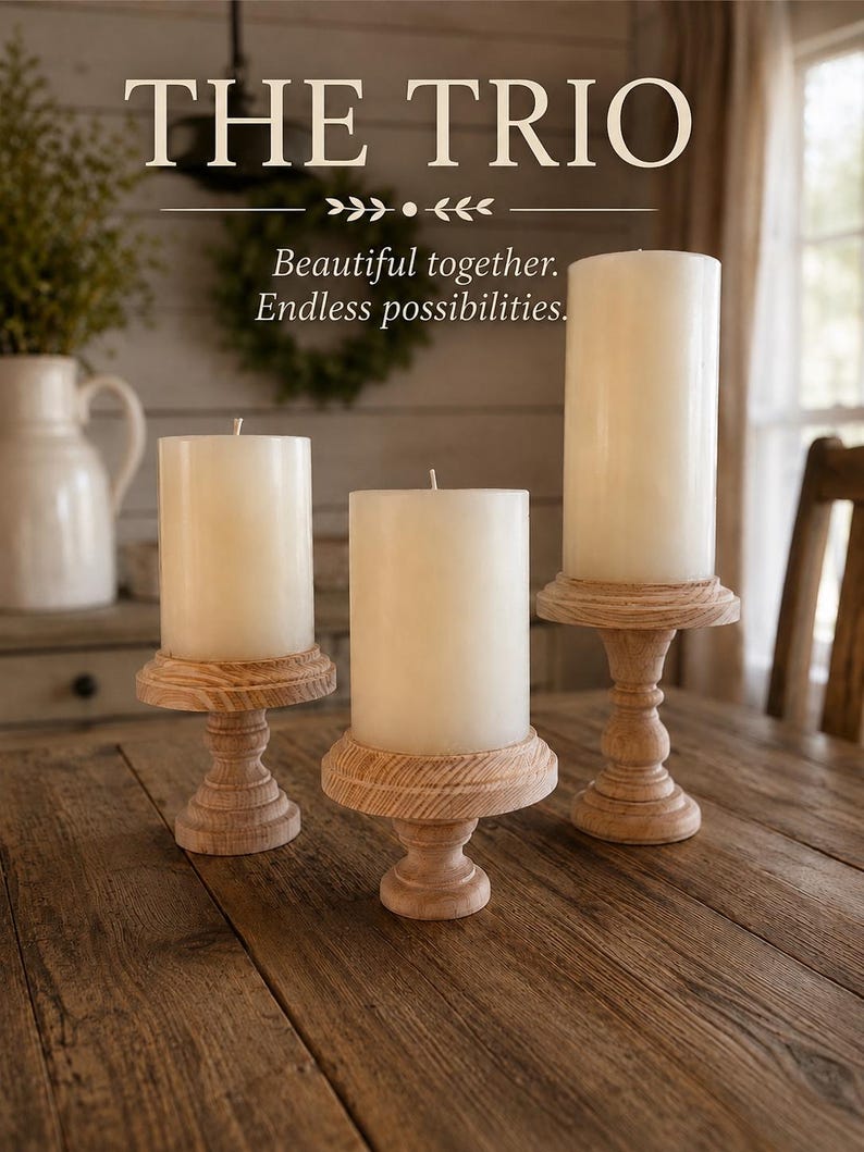 May include: Three ivory pillar candles on wooden pedestals. The candles are of varying heights and are displayed on a rustic wooden table. The text "THE TRIO" is at the top of the image, with the text "Beautiful together. Endless possibilities." below.