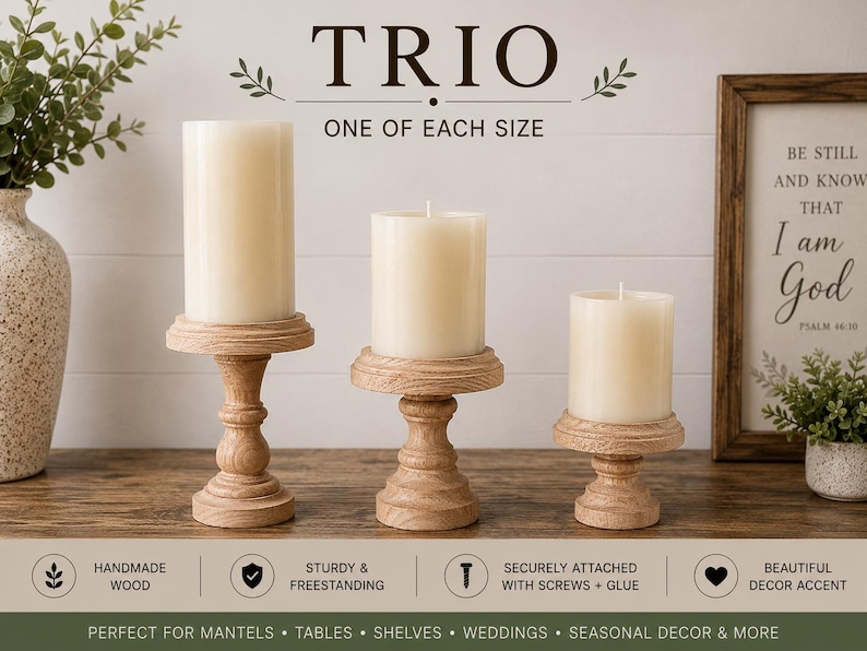 May include: A trio of wooden candle holders, each supporting a cream-colored pillar candle. The holders are in varying sizes and feature a turned design. The image includes the text "TRIO" and "ONE OF EACH SIZE".