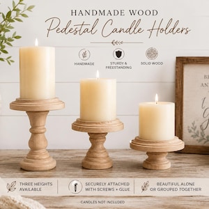 May include: Three handmade wooden pedestal candle holders with lit ivory candles. The candle holders are in varying heights and are made of solid wood. The text on the image says "Handmade Wood Pedestal Candle Holders".