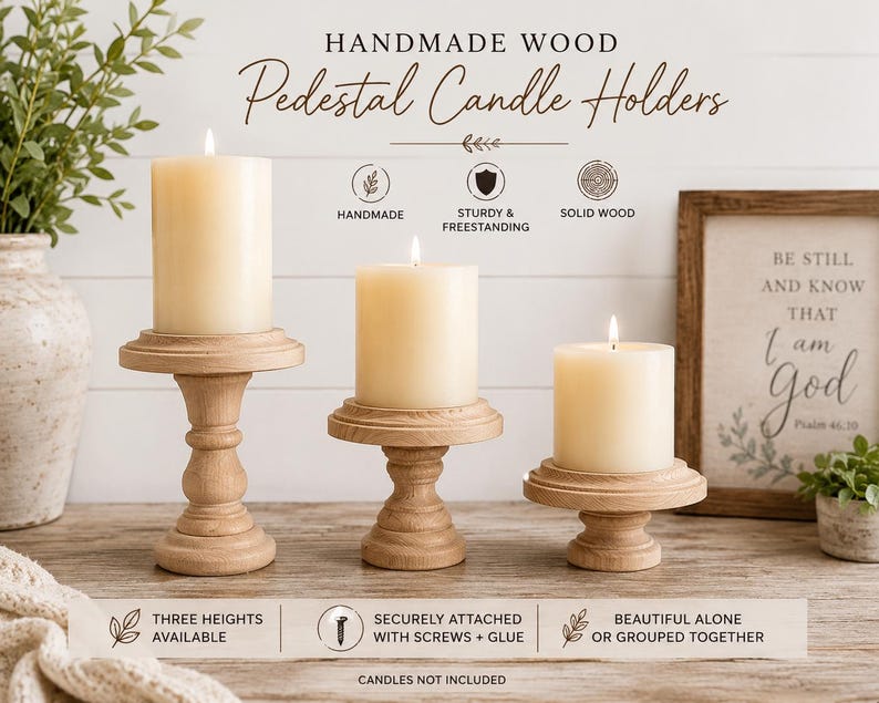 May include: Three handmade wooden pedestal candle holders with lit ivory candles. The candle holders are in varying heights and are made of solid wood. The text on the image says "Handmade Wood Pedestal Candle Holders".