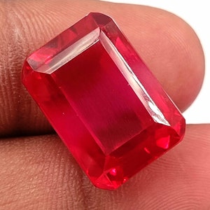 Puede incluir: Una piedra preciosa de color rojo intenso con un corte esmeralda rectangular.