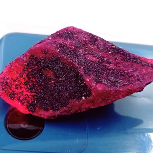 May include: A large, rough, pink and purple gemstone with a sparkly, crystalline texture.