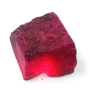 Può includere: Un grande rubino grezzo rosa scuro con una tonalità rossa al centro.