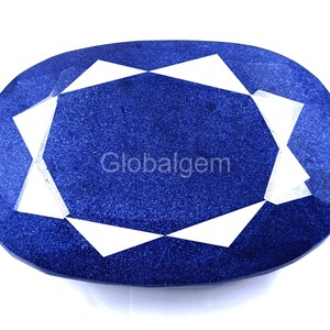 May include: Oval-shaped, deep blue gemstone with a faceted design. The center features a white geometric pattern, and the text "Globalgem" is visible. The gem is set against a white background.