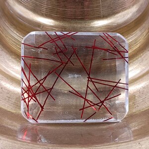 May include: A clear glass paperweight with a red and white geometric pattern.