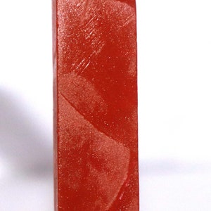 May include: A rectangular block of translucent red gemstone material with a smooth, polished surface. The stone features subtle internal variations and a deep, vibrant crimson hue throughout its solid, elongated, and uniform geometric shape.
