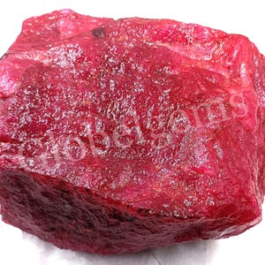 Peut inclure: Une grosse pierre précieuse de rubis rouge brute. Le rubis a une couleur rouge foncé et une surface texturée.