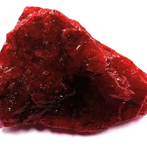 Może przedstawiać: Duży, surowy, czerwony rubin. Rubin ma intensywny czerwony kolor i naturalne, nieoszlifowane wykończenie.