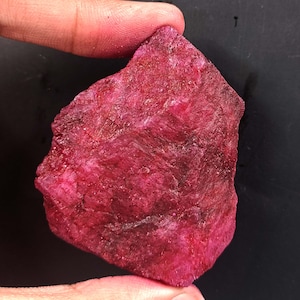 Op de afbeelding: Een grote, ruwe, rode robijn edelsteen. De robijn is diep rood van kleur en heeft een natuurlijke, onbewerkte afwerking.