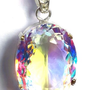 Puede incluir: Colgante de plata con una gran gema de corte ovalado. La gema muestra una vibrante gama de colores, incluyendo amarillo, rosa, azul y morado. El colgante está suspendido de una cadena de plata, creando una joya llamativa.