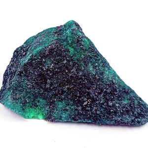 May include: A rough, dark green and black rock with a textured surface. The rock has a triangular shape and is about 5 inches long.