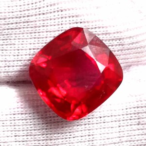 Può includere: Una pietra preziosa di colore rosso intenso con taglio a cuscino. La pietra preziosa è sfaccettata e ha un'alta lucidatura.