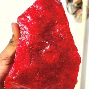 Puede incluir: Una gran gema de rubí rojo sin pulir. El rubí es de un color rojo intenso y rico y tiene una superficie ligeramente texturizada.