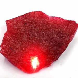 May include: A large, rough, red gemstone with a slightly translucent, glowing center.