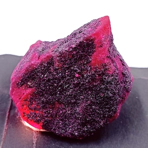 May include: A large, rough, pink and purple gemstone with a crystalline texture.