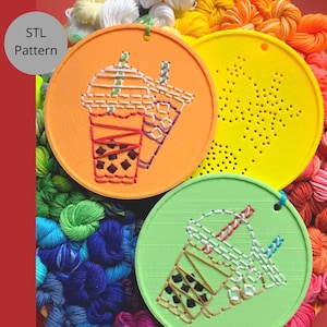 May include: Three round coasters in orange, yellow, and green, each featuring a stitched design of a bubble tea drink. The orange coaster has two bubble tea designs. The yellow coaster has a perforated starburst pattern. The coasters are surrounded by colorful embroidery floss.