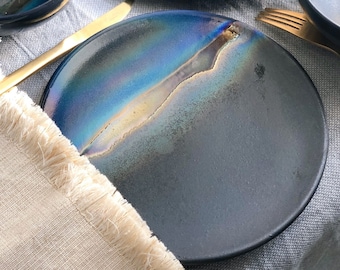 Puede incluir: Un plato de cerámica azul oscuro con un acabado de esmalte craquelado. El plato tiene un brillo iridiscente único y un sutil efecto craquelado.