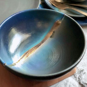 以下が含まれることがあります： 金色のひび割れ釉薬をかけた青い陶器のボウル。ボウルは深く丸みを帯びた形をしていて、滑らかで光沢のある仕上がりです。