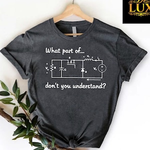 May include: Dark gray t-shirt with the text "What part of... don't you understand?" and a white circuit diagram. The shirt is hanging on a wooden hanger.