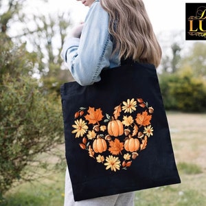 a woman carrying a black bag with a heart made of pumpkins and daisies