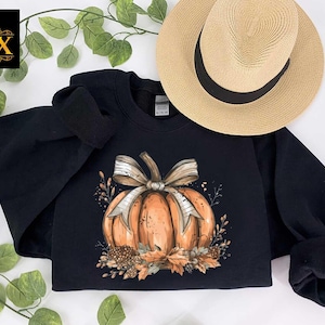 a black sweatshirt with a pumpkin and bow on it