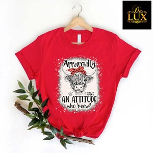 a red shirt with an image of a cow wearing a bow