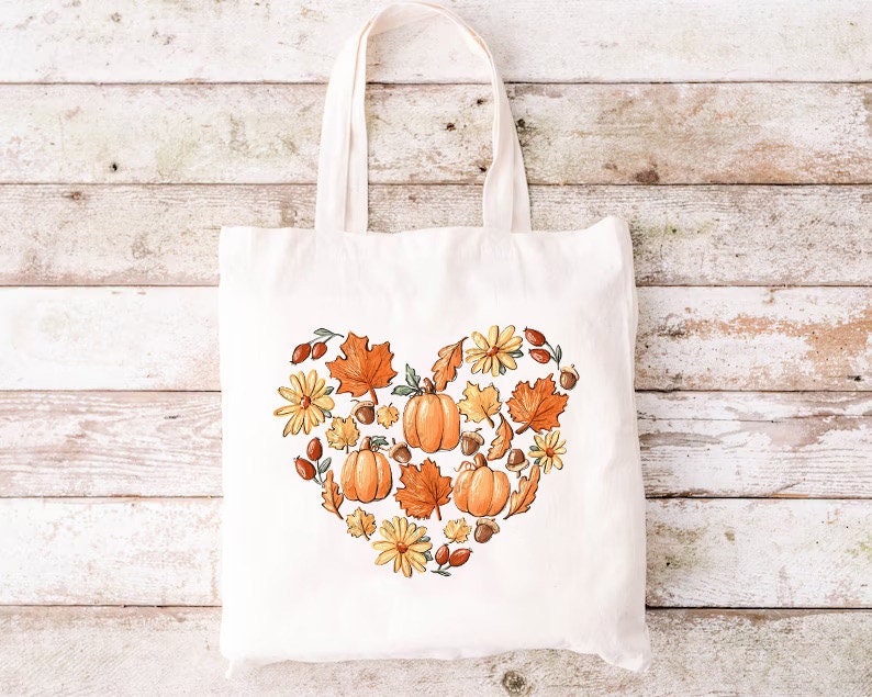 a white tote bag with a heart made of pumpkins and leaves