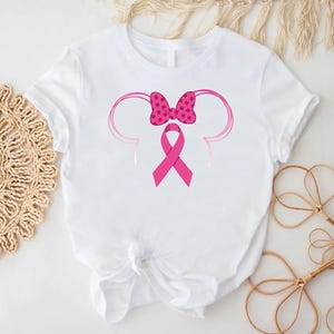 a minnie mouse shirt with a pink ribbon on it