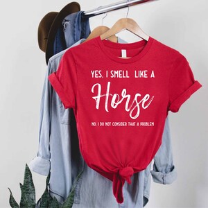 a red shirt that says yes i smell like a horse