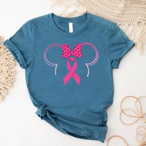 a blue shirt with a pink ribbon and minnie mouse ears