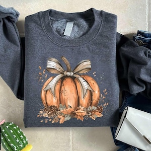 a gray shirt with a pumpkin and a bow on it