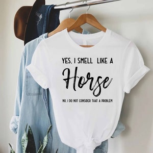 a white shirt that says, yes i smell like a horse in it's