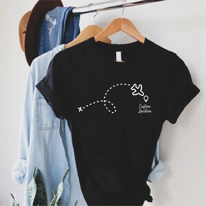 a t - shirt hanging on a clothes rack next to a hat