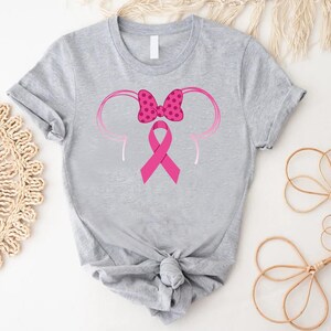 a gray shirt with a pink ribbon and minnie mouse ears