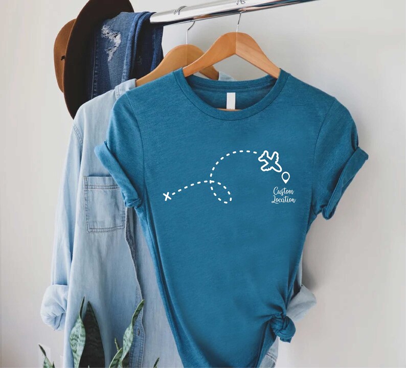 a t - shirt hanging on a clothes rack next to a hat