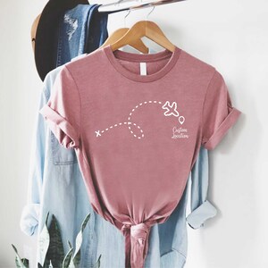 a t - shirt hanging on a clothes rack next to a plant