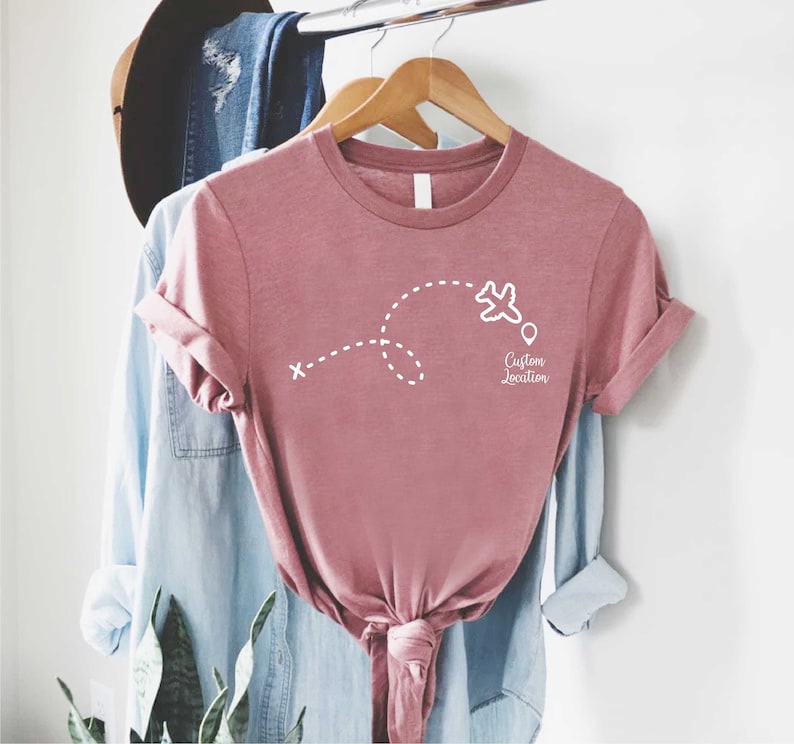 a t - shirt hanging on a clothes rack next to a plant