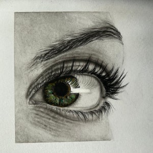 Puede incluir: Un primer plano de un dibujo en blanco y negro de un ojo humano con iris verde. El ojo mira hacia la derecha de la imagen.