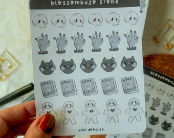 May include: A sheet of stickers featuring various Halloween-themed illustrations, including skulls, hands, cats, books, and gingerbread people. The stickers are black and white and have a vintage aesthetic. The sheet is labeled "blossombujo store" and "Noir doodles".