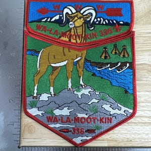 May include: Embroidered patch with a red border featuring a ram, mountains, and a river scene. The patch includes the text "WA-LA-MOOT-KIN 336". The top section has a blue background with a red arrow and the letter "W".