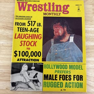 May include: A vintage "Wrestling Monthly" magazine from March 1974. The cover is yellow with the title in large pink letters. Features include a wrestler, a woman, and text: "From 517 lb. Teen-Age Laughing Stock to $100,000 Attraction."