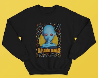 Könnte beinhalten: Schwarzes Sweatshirt mit einer blauen Alienfigur aus dem Film "La Planète Sauvage" (Fantastic Planet). Das Alien hält eine kleine menschliche Figur in seiner Hand. Der Text "LA PLANETE SAUVAGE" ist in Gelb mit roten und blauen Akzenten gedruckt.