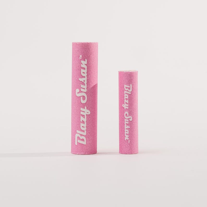 May include: Two pink Blazy Susan cigarette filters, one larger than the other, on a white background.
